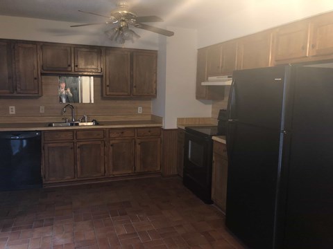 A kitchen with wooden cabinets and black appliances.