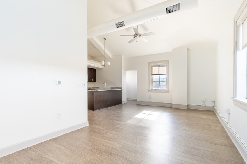 an empty living room with white walls and a ceiling fan