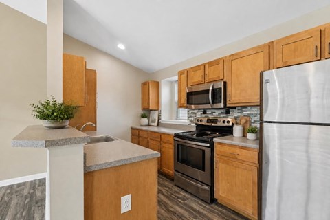 A kitchen with wooden cabinets and a stainless steel refrigerator.