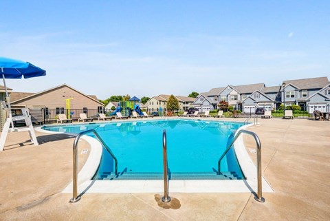 A large blue swimming pool with a ladder and a blue umbrella.