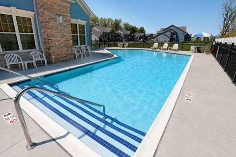A pool with a blue tiled edge and a metal handrail.