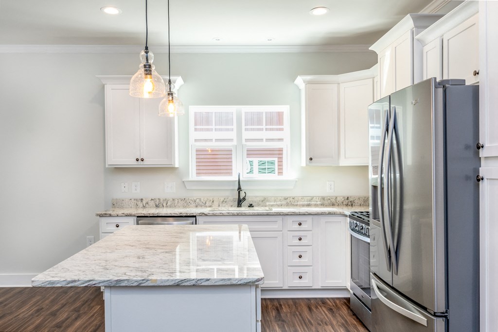 a white kitchen with stainless steel appliances and marble counter tops