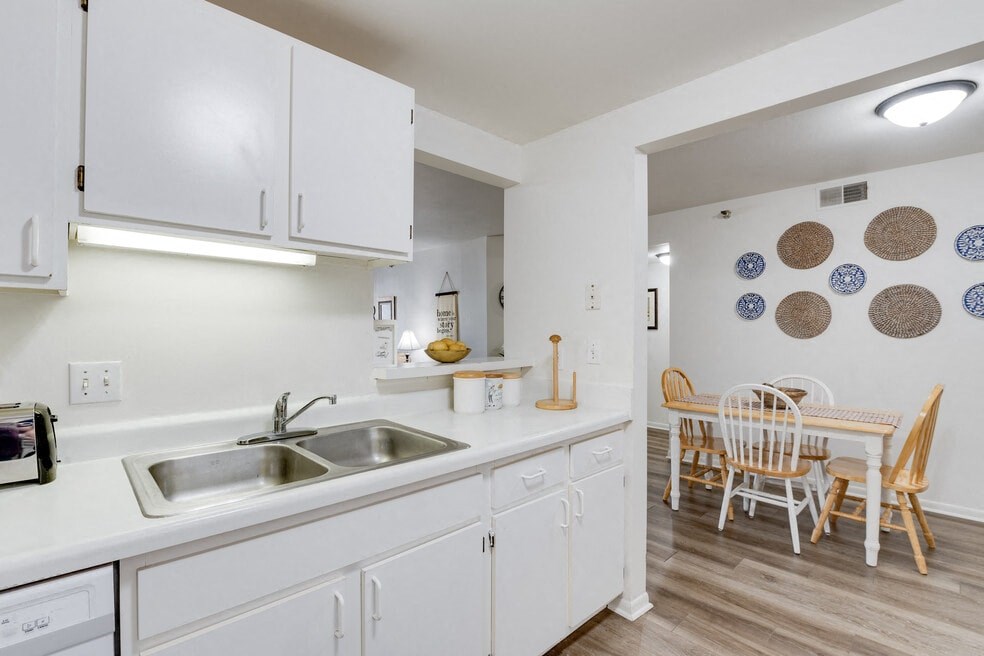 a kitchen with white cabinets and a dining room with a table and chairs