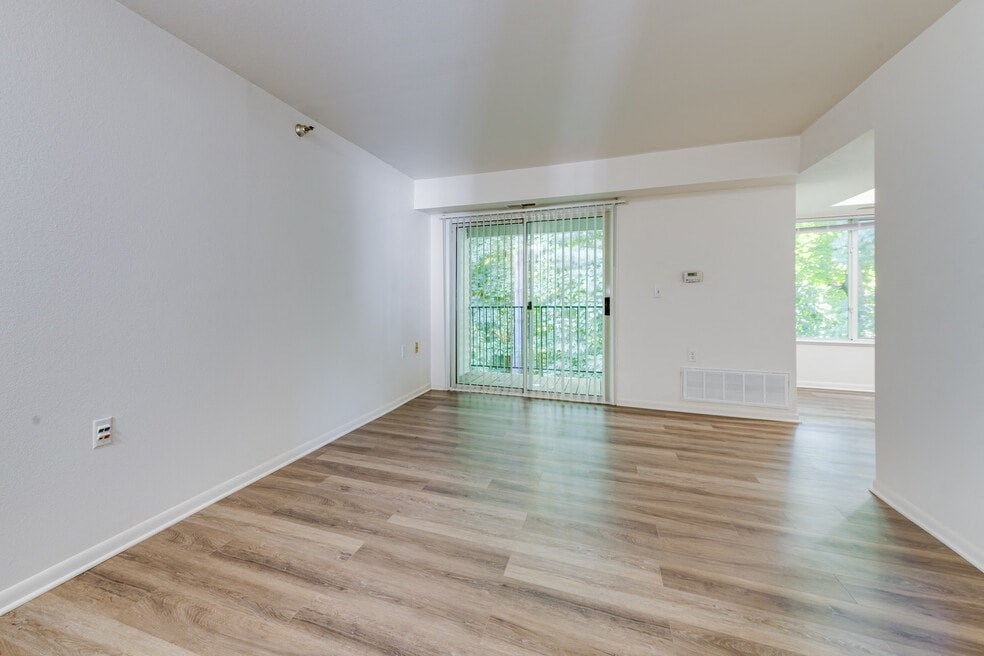 the living room and dining room of a house with white walls and wood flooring