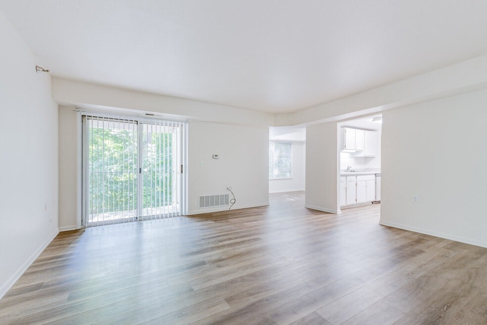 an empty living room with wood floors and a sliding glass door