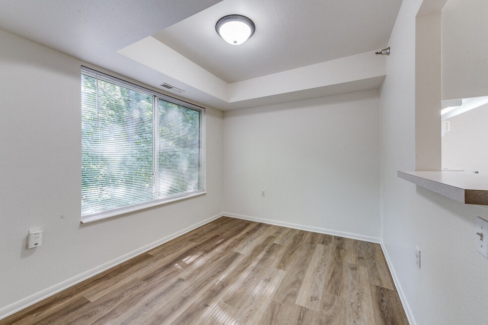 an empty living room with a large window and wood flooring