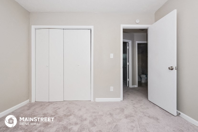 a bedroom with white closets and a carpeted floor