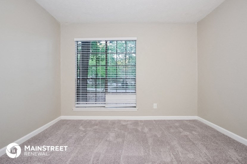 the spacious living room with a window and carpeted flooring