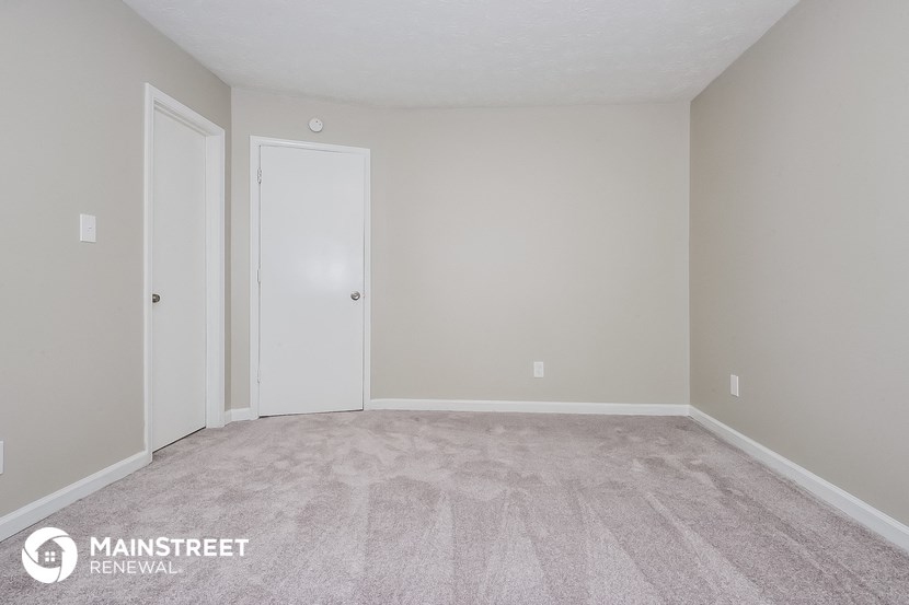 the spacious living room with carpeted flooring and white doors