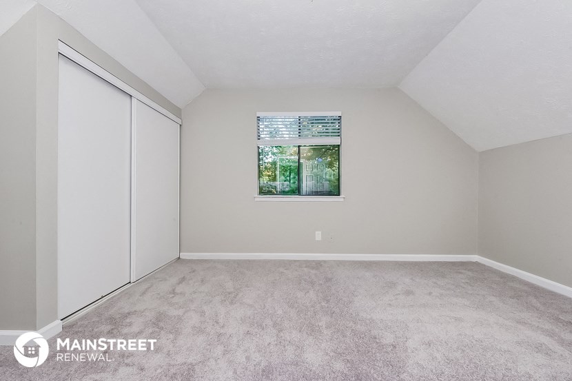 the living room of a manufactured home with carpet and a window