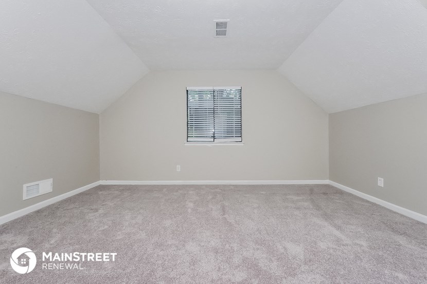 the spacious living room with carpeting and a window