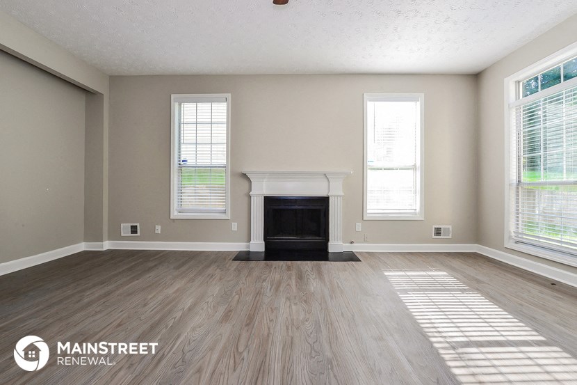 an empty living room with a fireplace and wooden floors