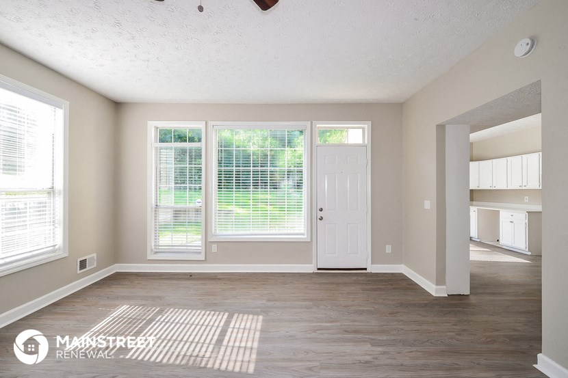 an empty living room with a white door and window