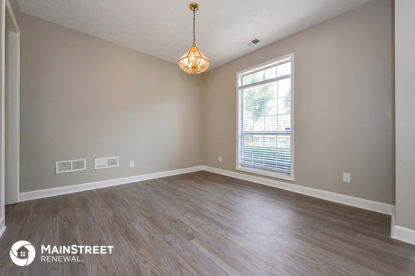 an empty living room with a large window and wood floors