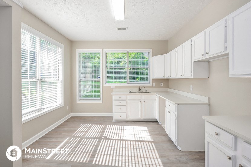 a large white kitchen with white cabinets and windows