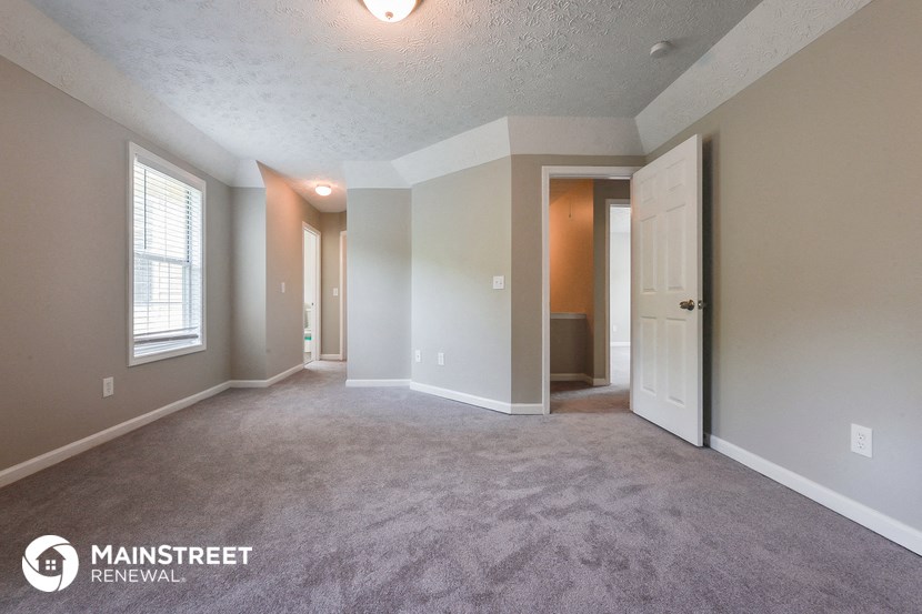 an empty living room with a white door and a window