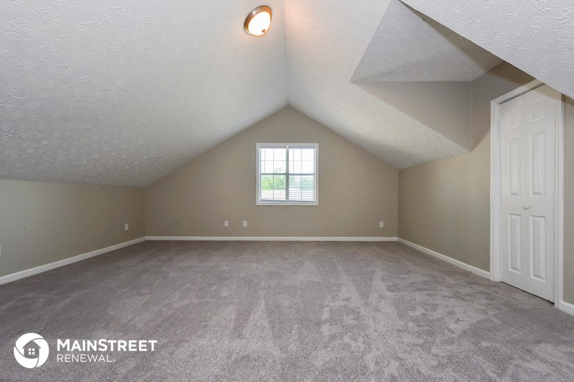 the upstairs loft of a house with a white door and a window