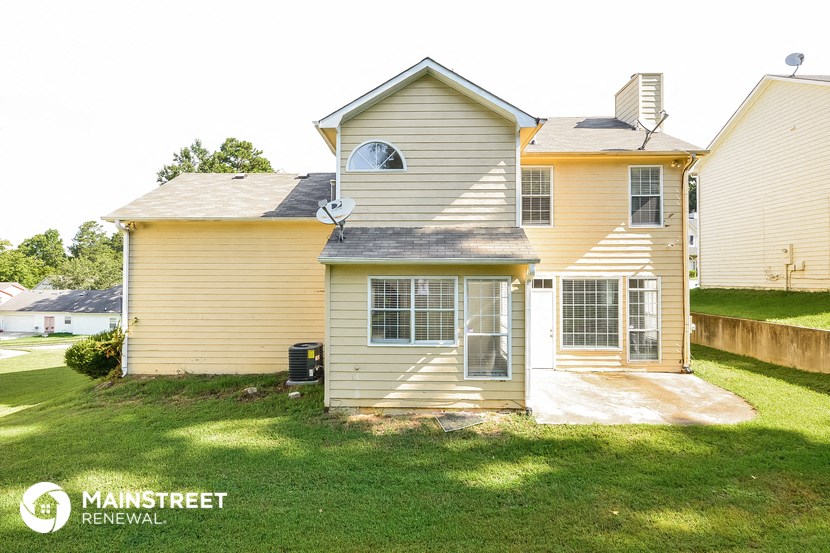 the front of a yellow house with a yard and grass