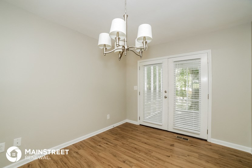 a living room with a chandelier and a door to a balcony