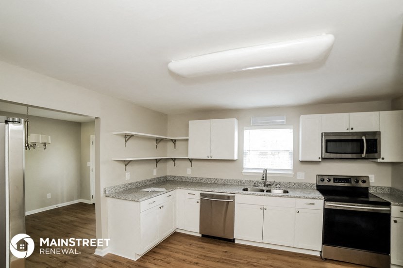 an empty kitchen with white cabinets and stainless steel appliances
