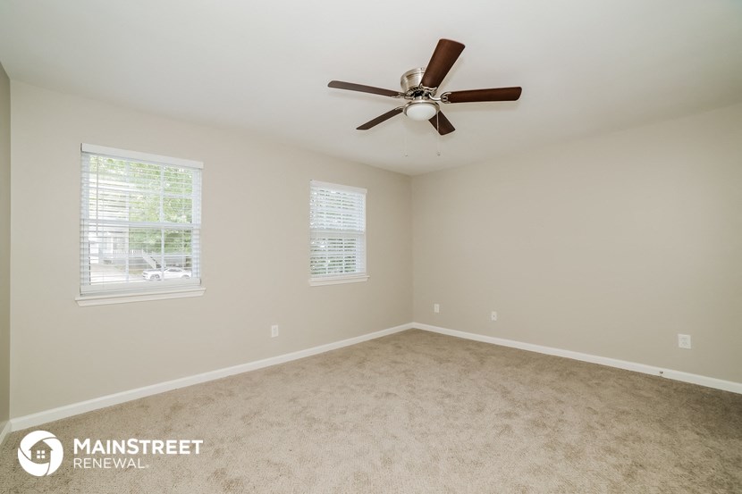the master bedroom has a carpeted floor and a ceiling fan