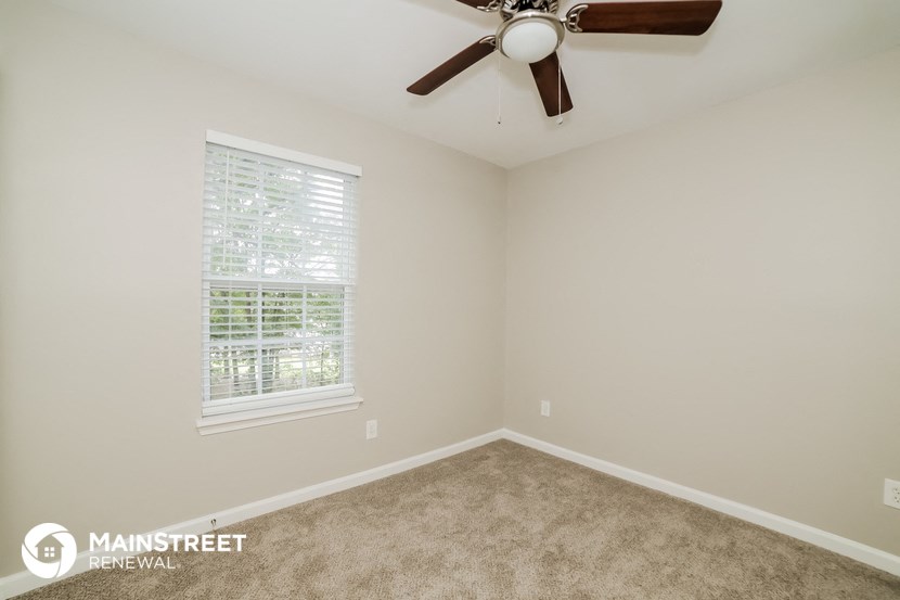 the upstairs bedroom has a ceiling fan and beige carpet