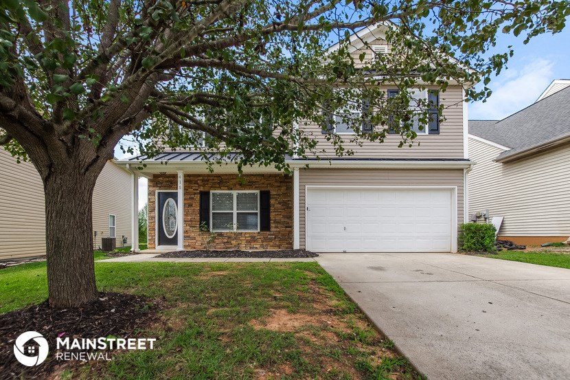 a house with a driveway and a tree in front of it