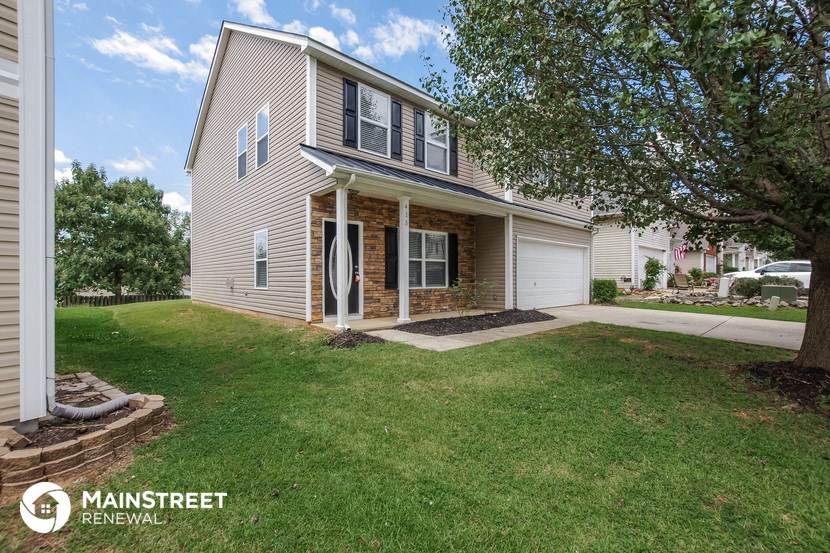 a home with a lawn and a tree in front of it