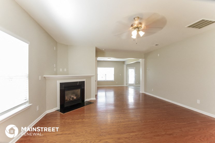 an empty living room with a fireplace and a ceiling fan