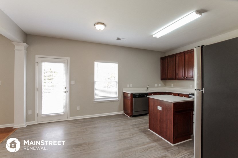 a kitchen with wood flooring and a refrigerator and a sink
