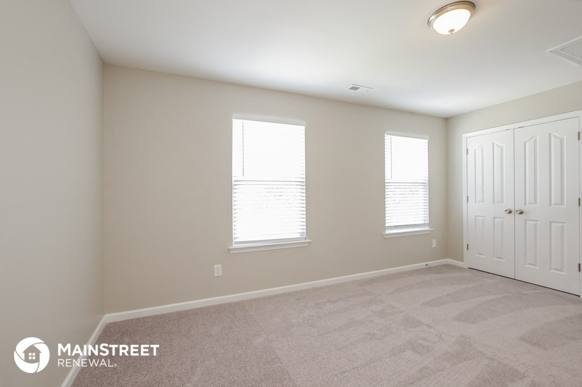a bedroom with three windows and a door and a carpeted floor