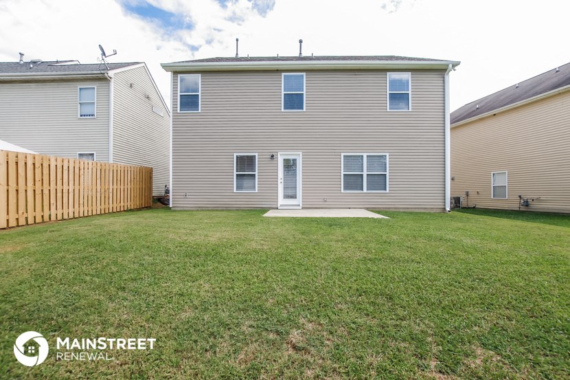 the backyard of a house with a yard and a wooden fence