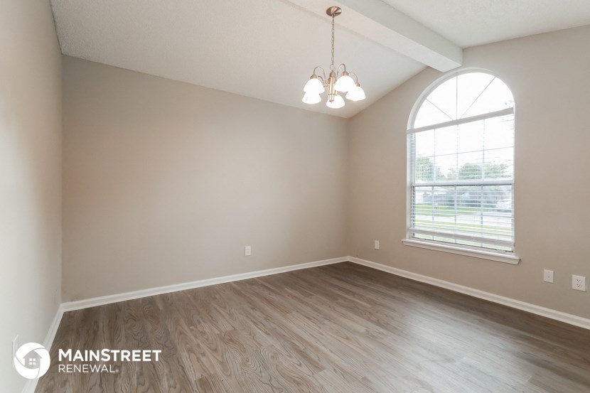 the spacious living room with wood flooring and a large window