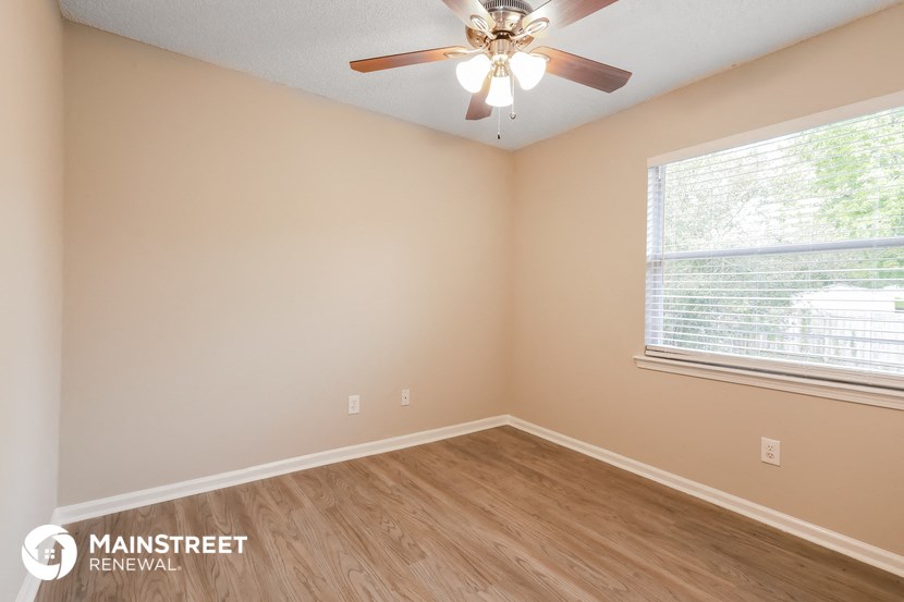 the interior of a bedroom with wood floors and a ceiling fan