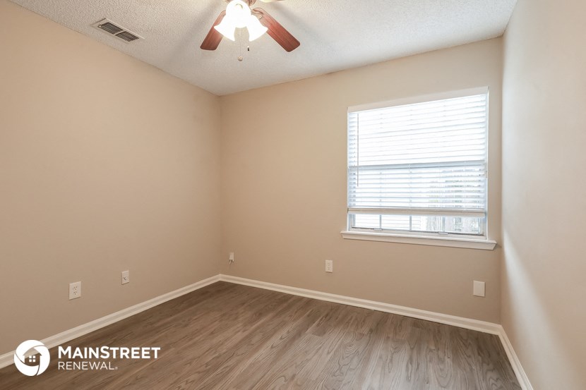 the interior of a bedroom with wooden floors and a ceiling fan