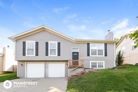 a white house with two garage doors and a green lawn