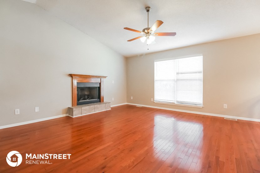 the living room with wood floors and a fireplace