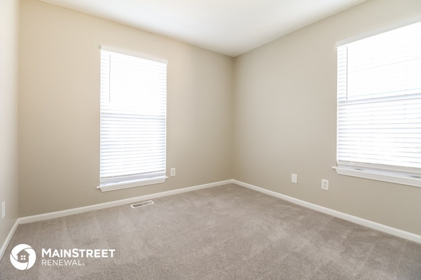 a spacious room with two windows and a carpeted floor