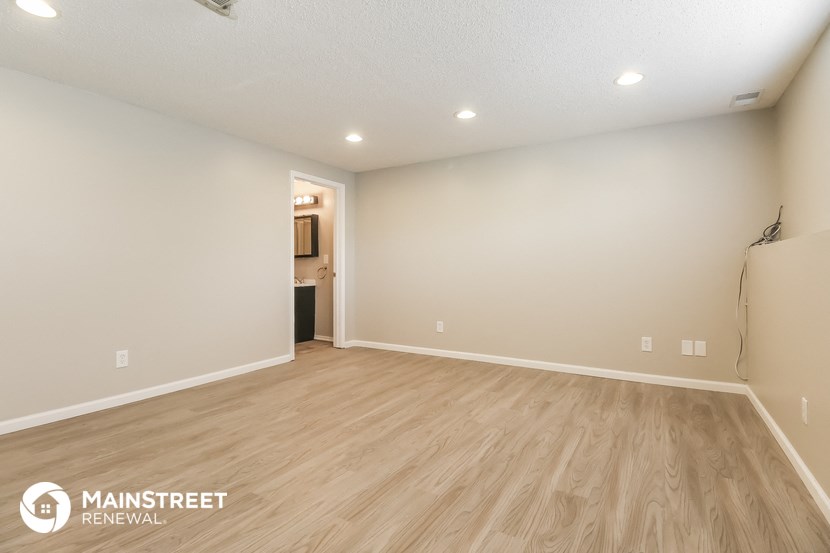 the spacious living room with wood flooring and white walls