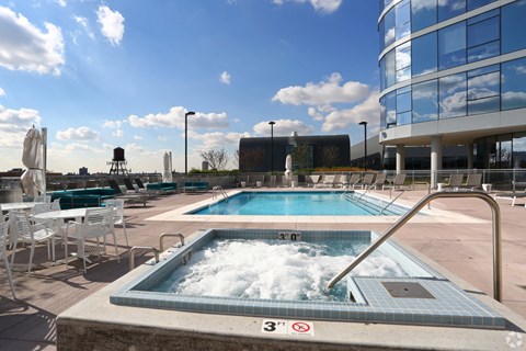 a jacuzzi on the rooftop of a building with a pool and chairs