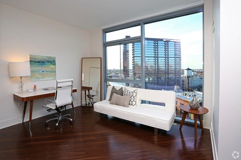 a living room with a couch and a desk and a large window