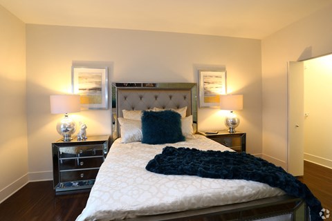 a bedroom with a bed and two nightstands and a mirror on the wall