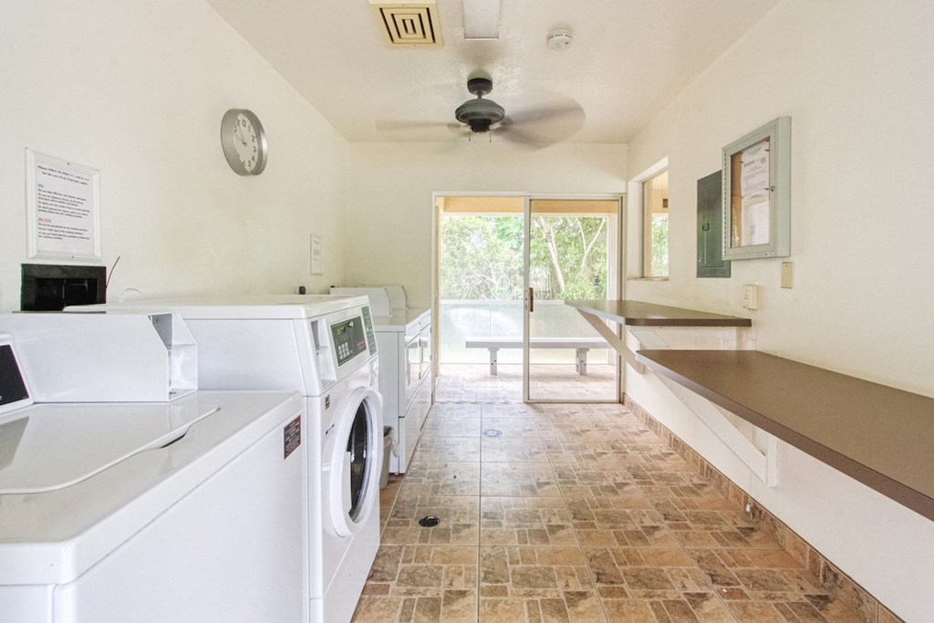 laundry room with washers, dryers, folding tables, and ceiling fan