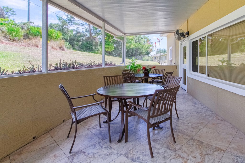 Patio with tables, chairs, and fan, and large windows
