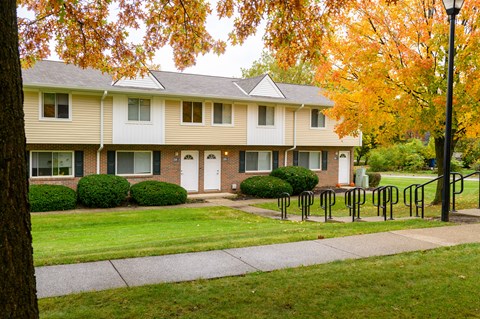 a house with a sidewalk in front of a lawn and trees