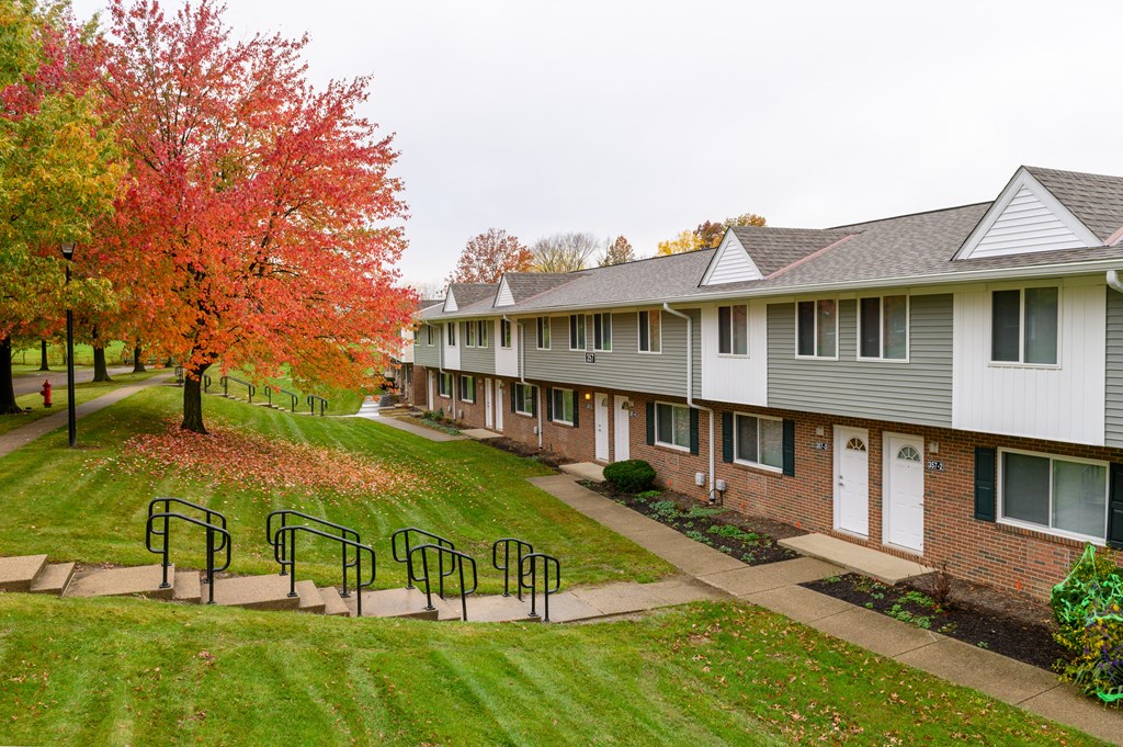 a row of houses with a lawn and trees in front of them