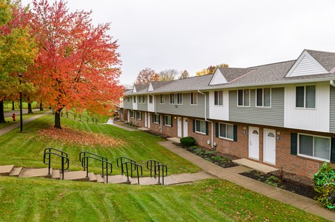 a row of houses with a lawn and trees in front of them