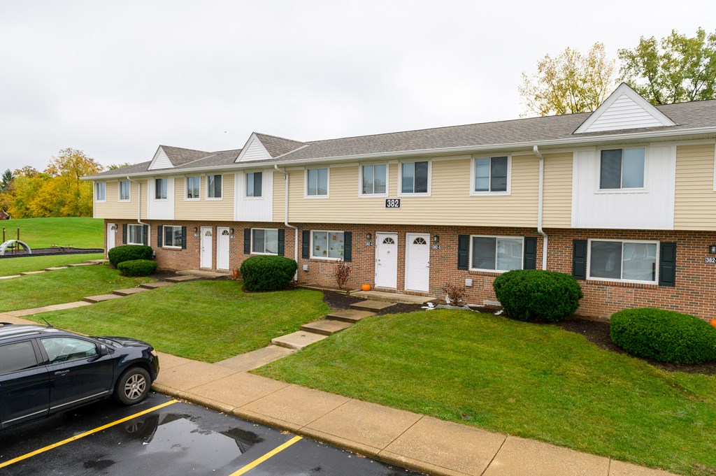 an apartment building with a lawn and a parking lot