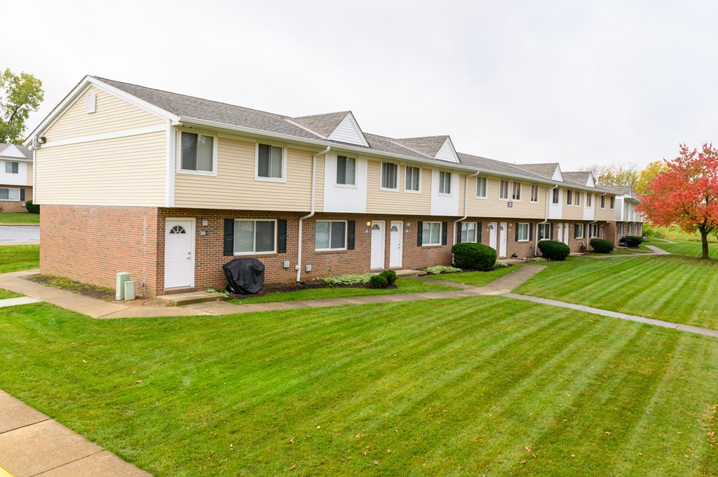 a row of townhomes with a green lawn and grass