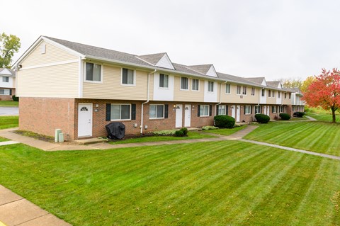 a row of townhomes with a green lawn and grass